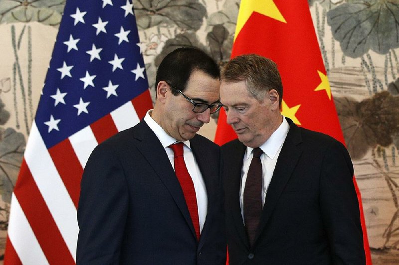Treasury Secretary Steve Mnuchin (left) and U.S. Trade Representative Robert Lighthizer confer Wednesday before a group photo session after their meeting with Chinese Vice Premier Liu He in Beijing. 