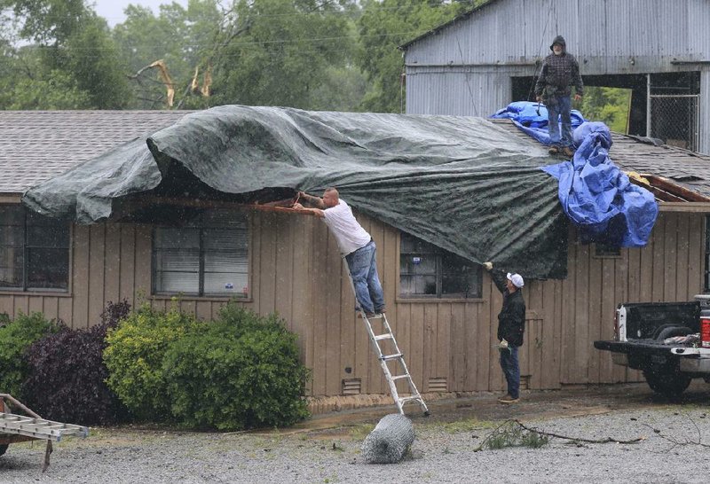 Workers put tarps on the roof of a building Thursday at Little Rock Fence Co. in the 11000 block of Interstate 30 after a storm passed through the area. More photos available at arkansasonline.com/53storms/ 