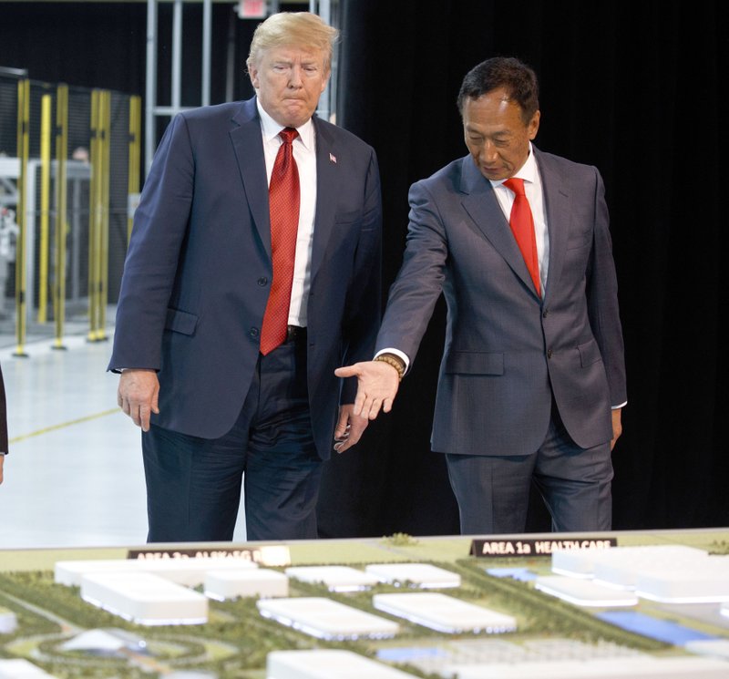 In this Thursday, June 28, 2018, file photo, President Donald Trump, left, takes a tour of Foxconn with Foxconn chairman Terry Gou in Mt. Pleasant, Wis. Gou says the Taiwanese company is moving forward with its plan to build a manufacturing facility in Wisconsin and President Donald Trump has promised to visit when production starts next year. Gou met with Trump on Wednesday to discuss the ever-changing project. Foxconn, the world's largest electronics company whose customers include Apple, Amazon and Google, plans to build a display screen factory in southeast Wisconsin. (AP Photo/Evan Vucci, File)