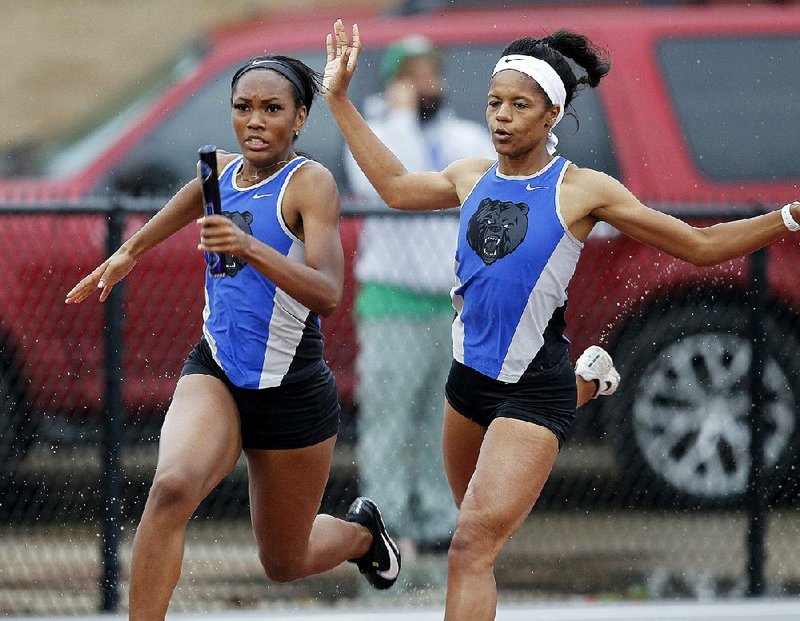 Mia Heard (left) of Sylvan Hills runs with the baton after taking a handoff from teammate Ayana Harris on the second leg of the 400-meter relay during the Class 5A state track and field meet at Lake Hamilton High School in Pearcy. Sylvan Hills won its third consecutive Class 5A state championship and fifth state championship overall. See more photos at arkansasonline.com/54track5a