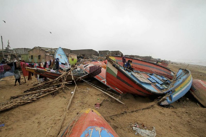 Children in Puri, India, sit Saturday on a boat damaged when Cyclone Fani struck the country’s Odisha state. 