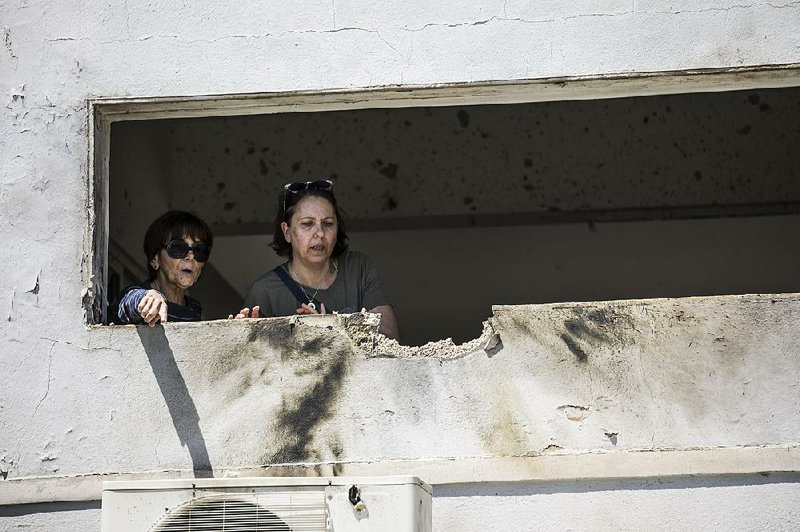 Women check the damage from a rocket fired from Gaza that hit a house in Israel on Saturday. Militants fired more than 250 rockets into southern Israel. 