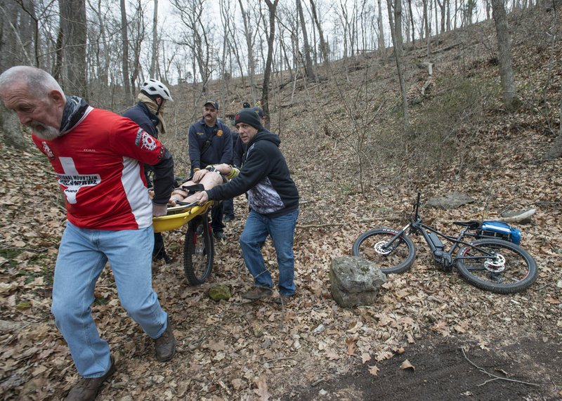 Arkansas Democrat-Gazette/SPENCER TIREY Brad Sandison, left, with Oz Mountain Bike Patrol along with Steve Pereira, right, also with the patrol work with Bentonville firemen to take a medical dummy off the Armadillo's Last Stand bike trail at Slaughter Pen. Firemen and the patrol were training on ways they would execute a rescue of an injured biker on the many bike trails that are in Northwest Arkansas.