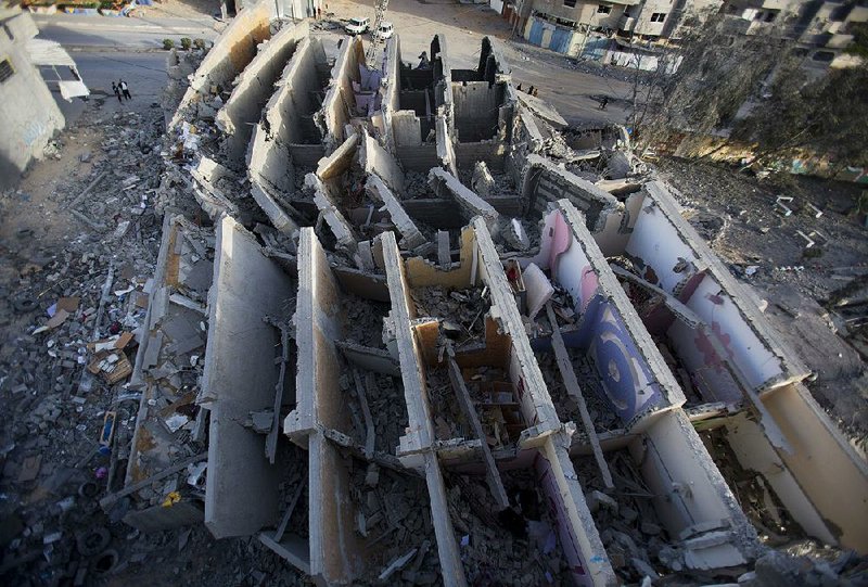 Palestinians on Monday check a multistory building that was hit and destroyed Sunday by Israeli airstrikes in Gaza City. 