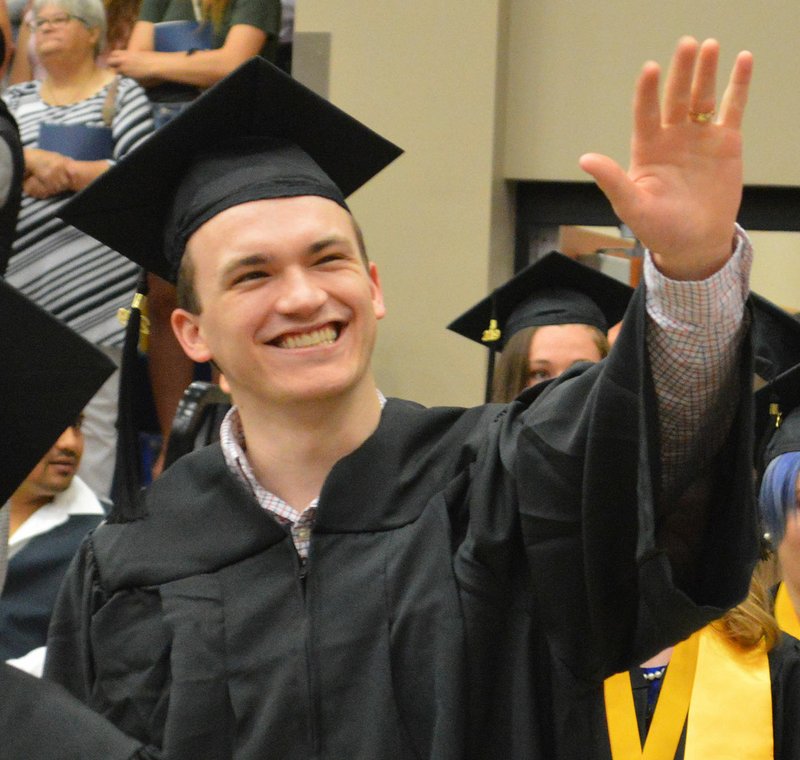 Sierra Bush/Herald-Leader A John Brown University undergraduate student waves to friends and family as he walks in the entering procession during the University's morning commencement ceremony Saturday. The University graduated 390 undergraduate, graduate and online students Saturday.