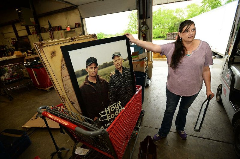 Terri Rutherford, manager of the Salvation Army Thrift Store in Fayetteville, shows a poster Wednesday for the fictional Hoyt Foods company, just one item from nine truckloads of True Detective items the store is putting up for sale. More photos are available at arkansasonline.com/59truedetective/ 