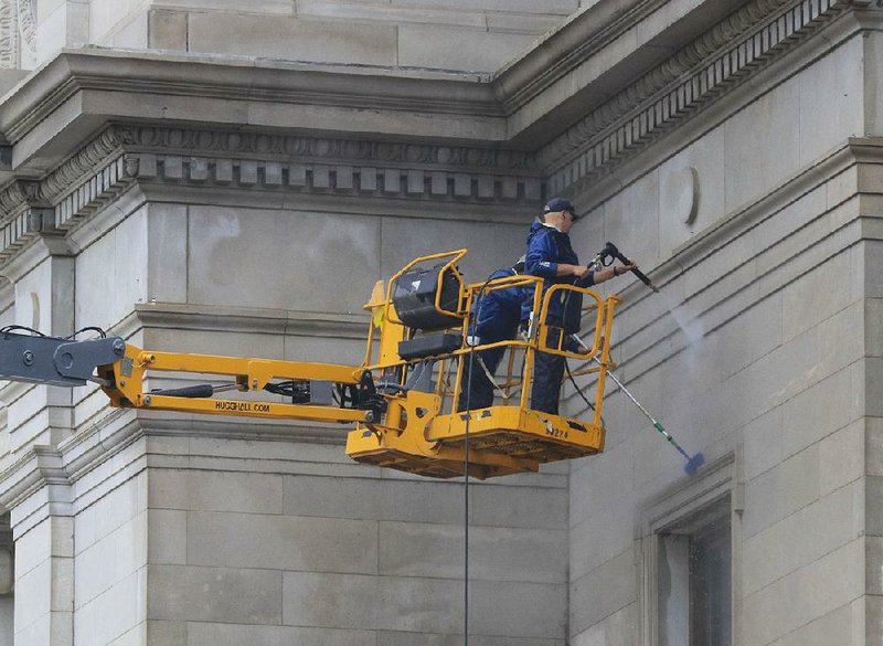 Brad Staley (left) and Josh Vance, with the secretary of state’s  office, work Wednesday afternoon power washing the front of the state Capitol. 