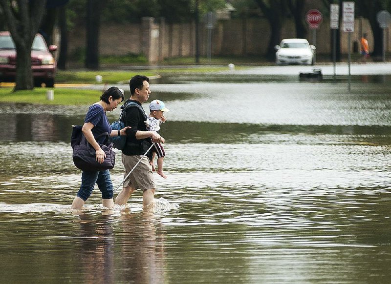 Hsien-Min Yeh and his wife, Julie, carry their 20-month-old baby, Winston, back to their home Wednesday after spending the night in their car because of high water and heavy rain in the Colony Bend area of Sugar Land, Texas. 