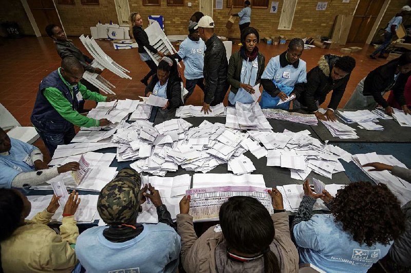 Party representatives watch Wednesday as election workers at a school in Johannesburg count ballots after polls closed in the national election. 