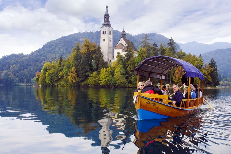 Visitors enjoy a scenic ride to a Lake Bled island on a traditional pletna boat. Photo by Cameron Hewitt via Rick Steves' Europe