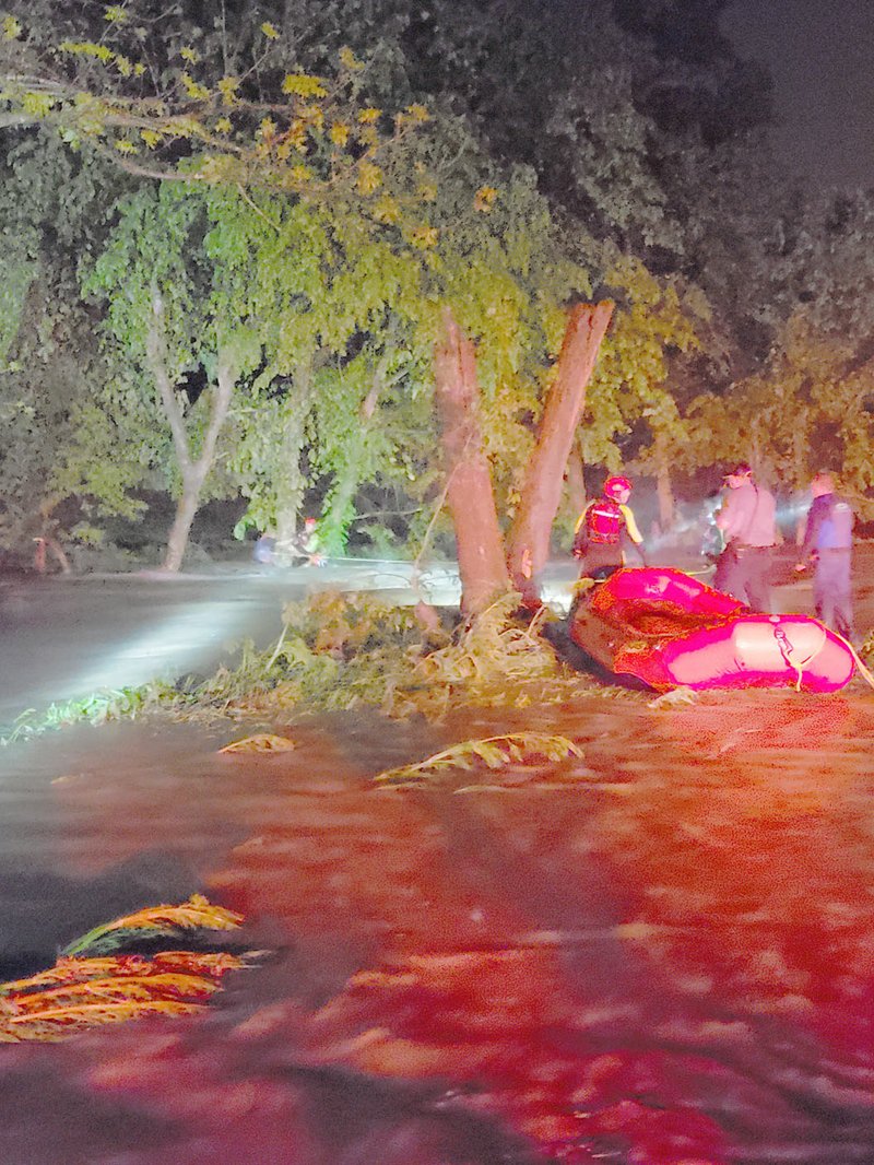 Photo courtesy of firefighter-paramedic Brian Heffington Bella Vista firefighters work to rescue a man clinging to a tree near a flooded low-water bridge on Little Missouri Road in Pineville.