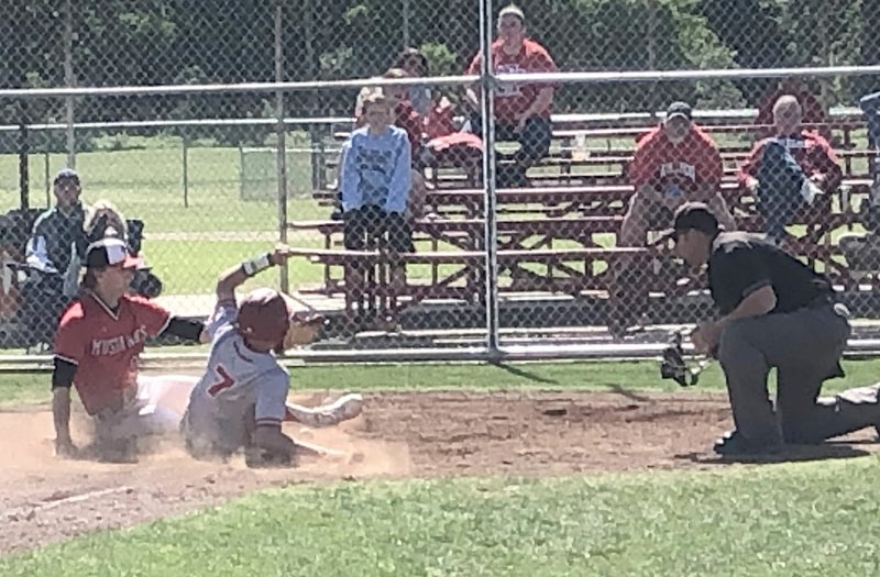 RICK PECK/SPECIAL TO MCDONALD COUNTY PRESS McDonald County pitcher Boston Dowd covers home plate as Carl Junction's Jackson Huffman scores in the bulldogs' 4-0 win on May 4 at Seneca High School.