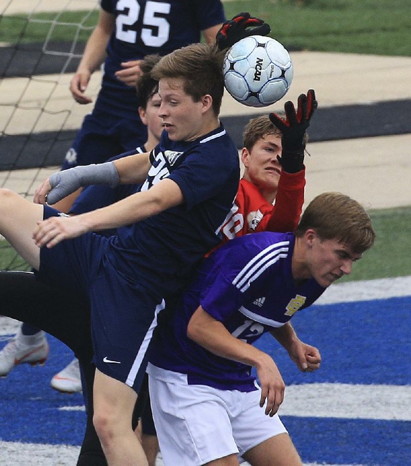 Bentonville West goalie Lleyton Hull (middle) grabs for the ball between his teammate Brayden Douthit (left) and Little Rock Catholic’s Rowan Thomas (right) during the opening round of the Class 6A state soccer tournament Thursday in Conway. Bentonville West won 1-0.