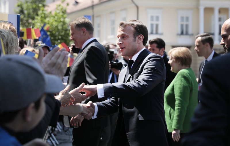 French President Emmanuel Macron, center, greets the public after a group photo of EU leaders at an EU summit in Sibiu, Romania, Thursday, May 9, 2019. European Union leaders on Thursday start to set out a course for increased political cooperation in the wake of the impending departure of the United Kingdom from the bloc. (AP Photo/Virginia Mayo)