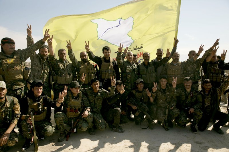 FILE - In this March 23, 2019 file photo, U.S.-backed Syrian Democratic Forces (SDF) fighters pose for a photo in Baghouz, Syria, after the SDF declared the area free of Islamic State militants. SDF defeated the IS in March but the Kurdish-led force is now facing protests by local Arab tribesmen in Deir el-Zour province. If the protests turn to an all-out uprising against the SDF it could be a blow to Washington as President Trump has plans to reduce America's military presence in Syria. (AP Photo/Maya Alleruzzo, File)