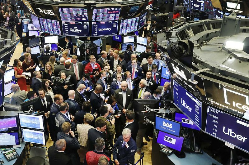 Traders gather around the post where Uber shares began trading Friday at the New York Stock Exchange. A hush fell over the chatty  crowd as the Uber stock began to sink. 