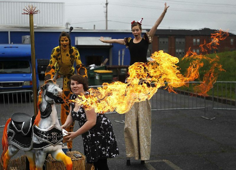 Whitney Waggoner (rear left) and Camille Rule, both with Arkansas Circus Arts, watch Saturday as Emily Jobe makes Pele the fire-breathing unicorn shoot fire from his mouth during the Mini Maker Faire at the Arkansas Regional Innovation Hub in North Little Rock. More photos are available at www.arkansasonline.com/512maker/ 