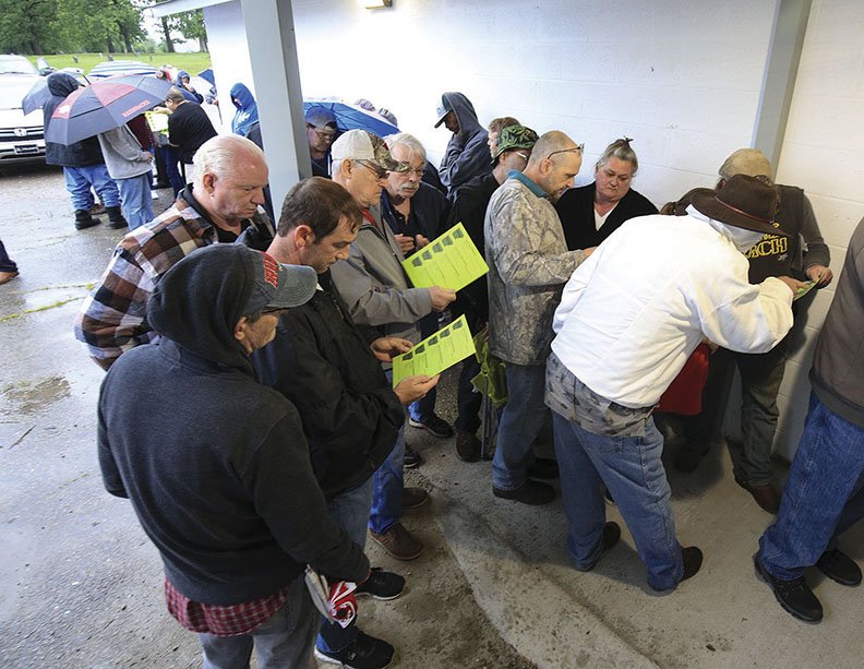 FILE — Customers look at the menu of products available outside Doctor's Orders RX medical marijuana dispensary in Hot Springs on May 11 as they wait in line for the business to open.