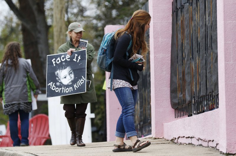 FILE - In this March 20, 2018, file photo, anti-abortion sidewalk counselors call out to a woman entering the Jackson Women's Health Organization's clinic, the only facility in the state that performs abortions, in Jackson, Miss. A new Mississippi law could make it nearly impossible for most pregnant women to get an abortion there if it survives a court challenge. (AP Photo/Rogelio V. Solis, File)