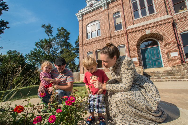 A staff member in a long 19th-century dress talks about pollination to a family outside the old courthouse at Powhatan Historic State Park. Photo via Arkansas Department of Parks and Tourism