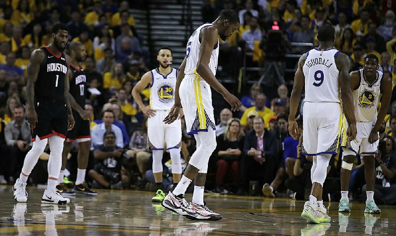 Golden State’s Kevin Durant limps off the court as Stephen Curry watches during the second half of Game 5 of the Western Conference semifinals against the Houston Rockets on Wednesday in Oakland, Calif. Durant likely will miss at least the first two games of the series.