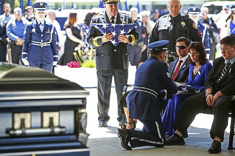 A U.S. Air Force Honor Guard member hands the folded flag that once draped the casket of slain Biloxi patrol officer Robert “Mac” McKeithen to his wife, Pamela McKeithen, during the officer’s funeral on Monday, at the Biloxi National Cemetery, in Biloxi, Miss. 