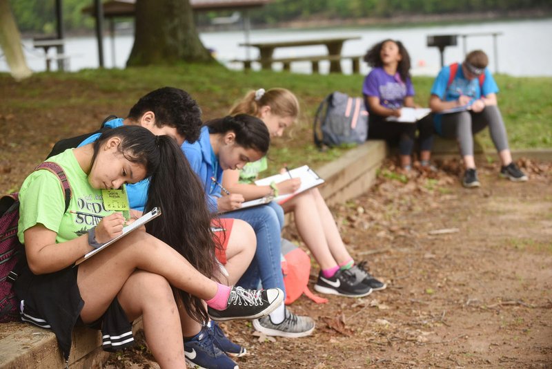 NWA Democrat-Gazette/FLIP PUTTHOFF Lingle Middle School outdoor writers, including Jasmine Andrade (left), work on their stories earlier this month at Prairie Creek park on Beaver Lake. Outdoor writing was one of many classes students could pick from at the 22nd annual Lingle Outdoor School for sixth-graders.