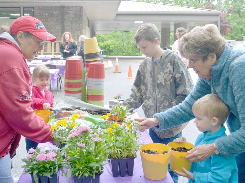 Keith Bryant/The Weekly Vista Susie Womack (left) with Village Wastewater, helps Jimmieann Long, 5, Jeremiah Lowe, 10, and Creek Lowe, 3, pick out flowers for Mother's Day flower pots, with a bit of assistance from the two boys' grandmother, Jerelyn Lowe.