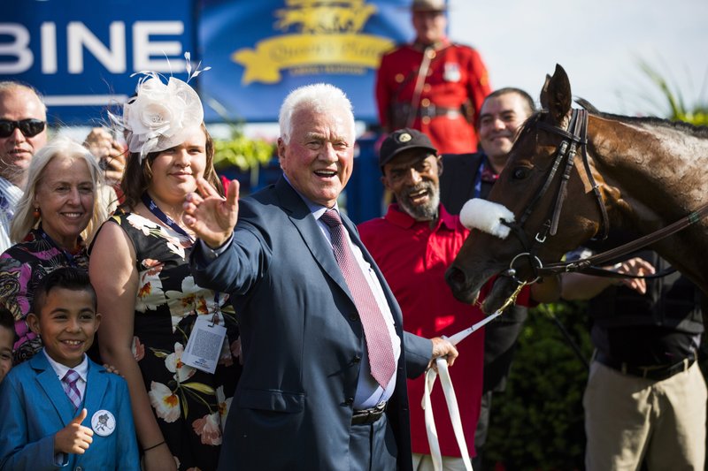 FILE - In this Sunday, July 2, 2017, file photo, Magna International founder Frank Stronach, center, poses with Holy Helena, right, after winning the Queen's Plate horse race at Woodbine Race Track in Toronto. The Stronach Group is a boon for business and a lightning rod for criticism because horse racing wouldn&#x2019;t be where it is right now without it, even if sometimes the attention is anything but positive. (Mark Blinch/The Canadian Press via AP, File)