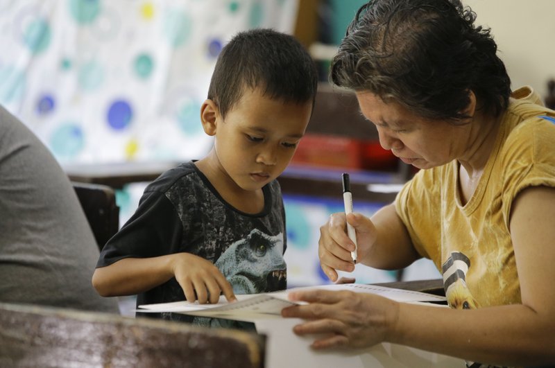 A Filipino boy looks as his mother votes during the country's midterm elections inside a polling center in Manila, Philippines on Monday, May 13, 2019. Filipinos voted in midterm elections highlighted by a showdown between President Rodrigo Duterte's allies who aim to dominate the Senate and an opposition fighting for check and balance under a leader they regard as a looming dictator. (AP Photo/Aaron Favila)