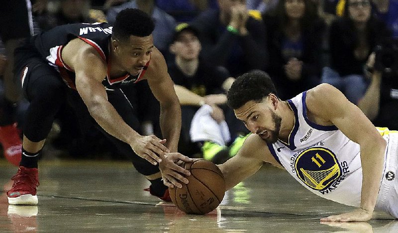 Golden State’s Klay Thompson (right) and Portland’s CJ McCollum reach for a loose ball Tuesday during the Warriors’ 116-94 victory over the Trail Blazers in Game 1 of the NBA Western Conference final in Oakland, Calif.