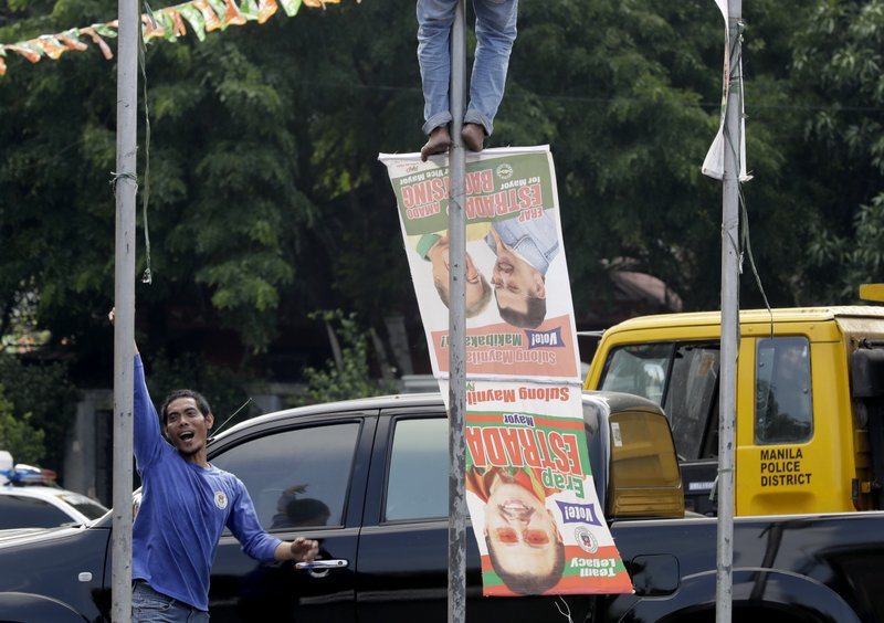Manila City public workers remove the campaign posters, mostly that of incumbent Mayor and former President Joseph "Erap" Estrada around the Manila City Hall, a day after the country's midterm elections Tuesday, May 14, 2019 in Manila, Philippines. Estrada lost his third term mayoral bid along with four of his children who ran in local polls, ending his 50-year-dominance in two metropolitan cities in the country.  (AP Photo/Bullit Marquez)