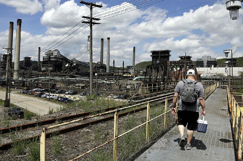 A worker arrives for his shift earlier this month at the U.S. Steel Clairton Coke Works in Clairton, Pa. U.S. factory production fell in April for a third time in four months, led by weakness in output of automobiles and auto parts. 
