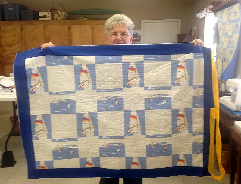 Sally Carroll/McDonald County Press DeeDee Lewis shows off a quilt created by local quilters who will show their creations at a quilt show on Saturday and Sunday at the Pineville Community Center. McDonald County neighbors are encouraged to contact Bunker Hill to bring and display their quilts as well. For information, call Lewis at 417-223-4835.
