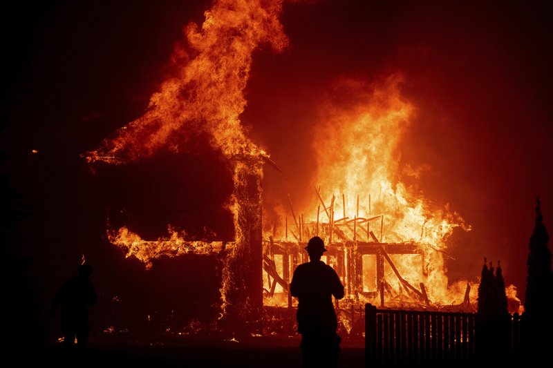 FILE - In this Nov. 8, 2018 file photo a home burns as the Camp Fire rages through Paradise, Calif. California fire authorities say that Pacific Gas and Electric equipment was responsible for the deadliest and most destructive wildfire in state history. Cal Fire said in a press release issued Wednesday, May 15, 2019, that electrical transmission lines in the Pulga area sparked the Nov. 8 fire that wiped out most of the town of Paradise and killed 85 people. (AP Photo/Noah Berger,File)