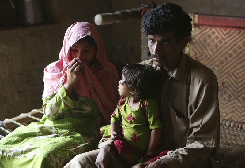 Pakistan's Tariq Ali, 30 along with his wife Parveen and three-year-old Ume Kulssom all infected with HIV sit at their home in a village near Ratodero, Thursday, May,16, 2019. Officials say about 500 people, mostly children, have tested positive for HIV, the virus that causes AIDS, in a southern Pakistani provincial district. A local doctor who has AIDS has since been arrested and is being investigated for possibly intentionally infecting patients. (AP Photo/Fareed Khan)