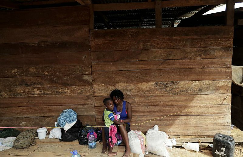 A migrant woman and her son rest under a house recently in Penitas, Panama, in Darien province. 