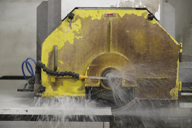 A computer operated wet saw cuts though an imported quartz slab from China as they begin production on a kitchen countertop at Marble Uniques in Tipton, Ind., Friday, May 3, 2019.  (AP Photo/Michael Conroy)