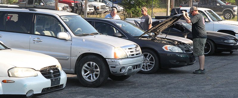 The Sentinel-Record/Richard Rasmussen CHECKING UNDER THE HOOD: Potential buyers look over some of the vehicles sold Friday at the 18th Judicial District East Drug Task Force auction at the Bill Edwards Center.