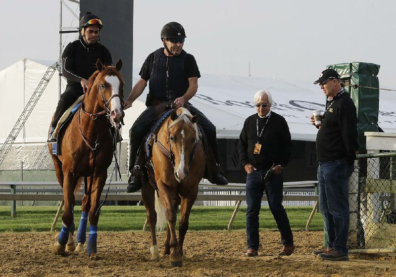 Improbable (left) is led back to the barn as trainer Bob Baffert (far right) watches during Friday’s training for today’s Preakness Stakes in Baltimore.