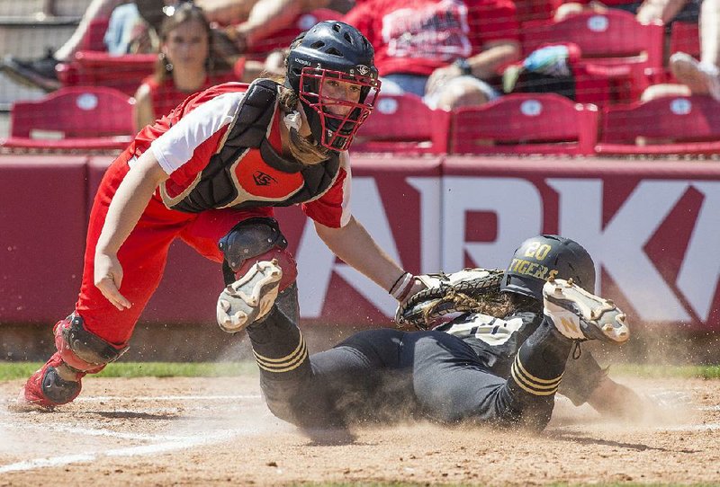 Cabot catcher Jaden Potter (left) tags out Bentonville’s Emily Perry at home plate during the fourth inning of the Lady Panthers’ 5-3 victory Friday in the Class 6A softball state championship game at Bogle Park in Fayetteville.