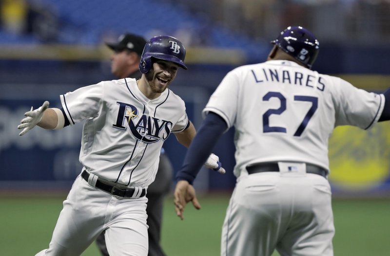 FILE - In this May 7, 2019, file photo, Tampa Bay Rays' Brandon Lowe, left, celebrates with third base coach Rodney Linares after hitting a home run off Arizona Diamondbacks pitcher Taylor Clarke during the first inning of a baseball game in St. Petersburg, Fla. They have a terrible stadium, hardly any fans and one of baseball's smallest payrolls. Yet, somehow, the Rays stay competitive year after year. It is one of the most compelling stories in sports, even if few people notice. (AP Photo/Chris O'Meara, File)