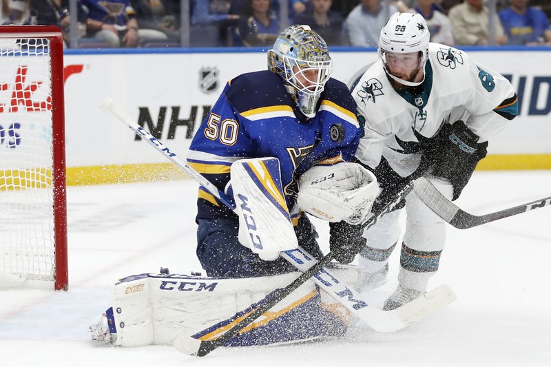 St. Louis Blues goaltender Jordan Binnington (left) protects the puck as San Jose Sharks center Melker Karlsson closes in Friday during the second period of Game 4 of the NHL hockey Stanley Cup Western Conference final series in St. Louis.