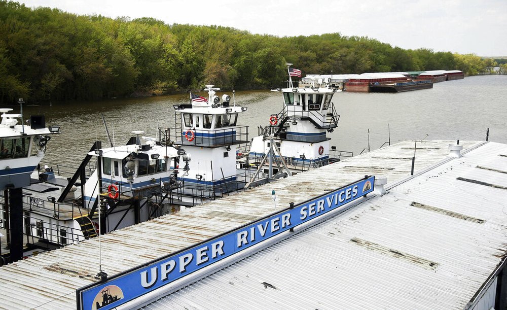 In this Tuesday, May 14, 2019 photo, empty barges, background right, are moored at the Upper River Services along with tug boats on the Mississippi River in St. Paul, Minn., as spring flooding interrupts shipments on the river. Historic Midwest flooding that began in March has left parts of the Mississippi River closed for business.