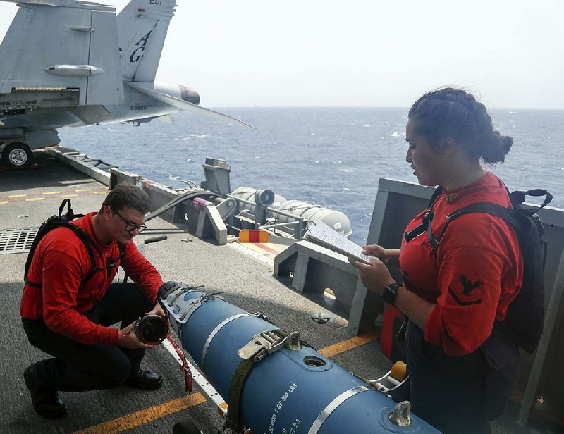 In this Navy-released photo Saturday, Aviation Ordnanceman Airman Hunter Musil and Aviation Ordnanceman 3rd Class Alexandrina Ross inspect a bomb Tuesday aboard the USS Abraham Lincoln as it sails in the Arabian Sea.