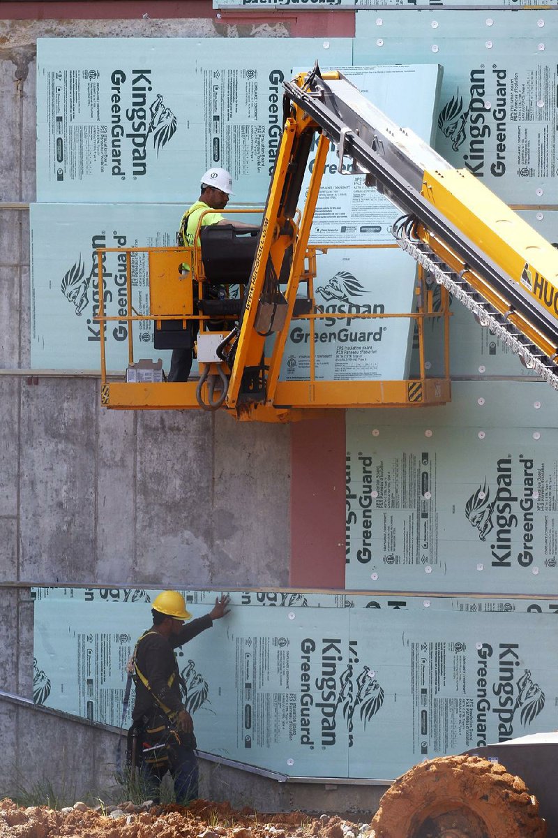 Construction workers fasten insulation board to a wall Friday at the new Jacksonville High School. 