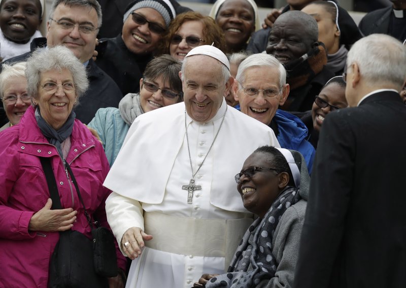 Pope Francis shares a laugh with a group of faithful as he poses for a family photo, at the end of his weekly general audience in St. Peter's Square, at the Vatican, Wednesday May 15, 2019. (AP Photo/Andrew Medichini)