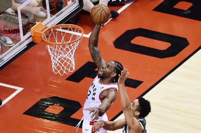 Toronto Raptors forward Kawhi Leonard scores past Milwaukee Bucks guard Malcolm Brogdon during the second overtime of Game 3 of the NBA Eastern Conference finals Sunday in Toronto. Leonard had 36 points, 9 rebounds and 5 assists to help the Raptors win 118-112.