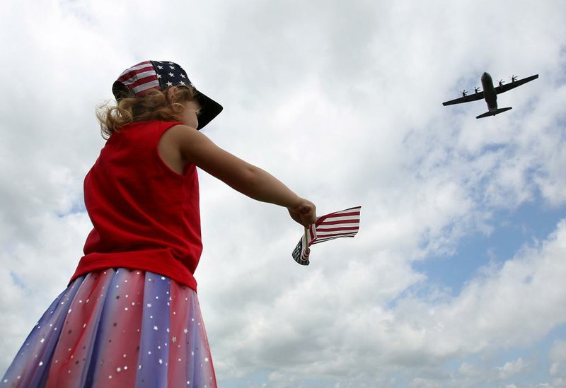 Savannah Hatfield, 4, of Maumelle waves a flag as her uncle, Capt. Ian Alpert's, C-130 flies over while returning from a deployment in southwest Asia on Sunday, May 19, 2019, at Little Rock Air Force Base in Jacksonville.