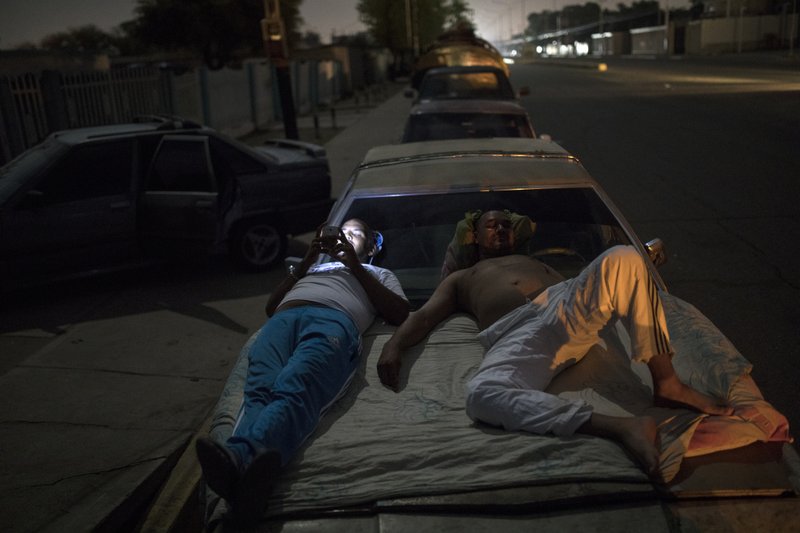 Andres Quintero, left, and Fermin Perez rest on top of Perez's car as they wait in line for over 20 hours to fill their tanks with gas in Cabimas, Venezuela, Thursday, May 16, 2019. U.S. sanctions on oil-rich Venezuela appear to be taking hold, resulting in mile-long lines for fuel in the South American nation&#x2019;s second-largest city, Maracaibo. (AP Photo/Rodrigo Abd)